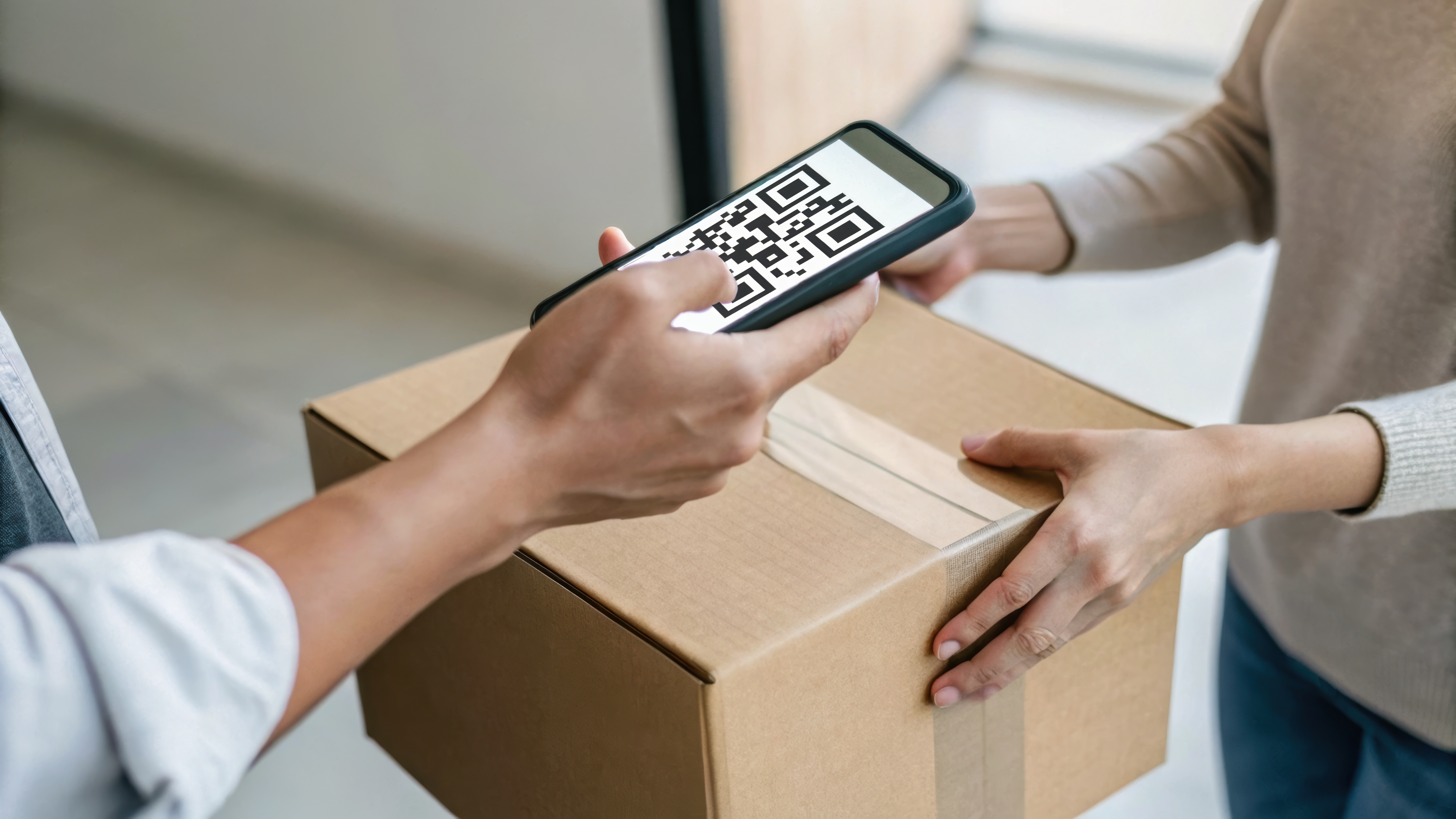 qr code stamped on a box with hands around it